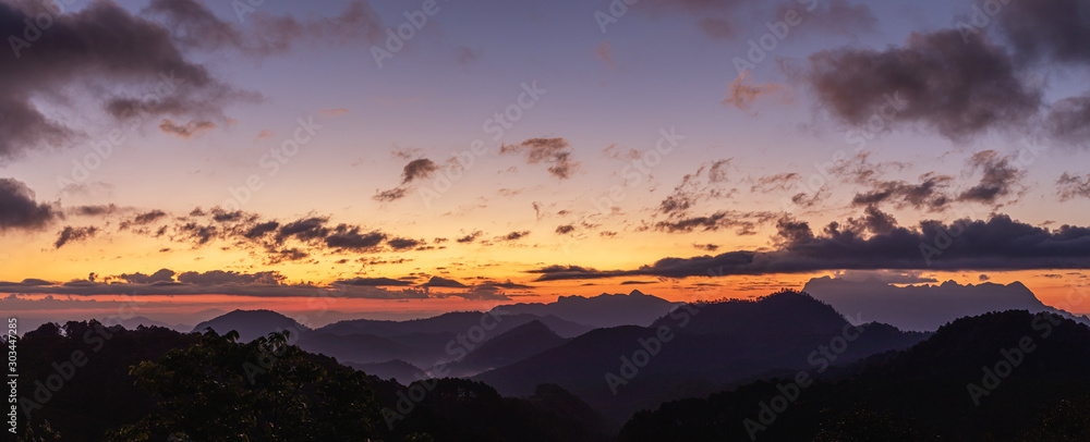 Layers of mountains line at sunset or sunrise with colorful sky panorama.