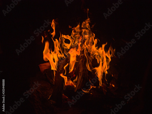 Bonfire flame on a dark background. Orange flames burn in the dark