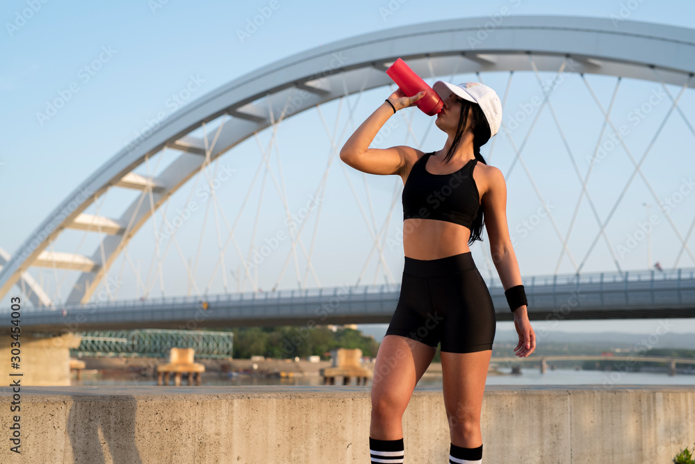 Fit, sexy female drinking water from sports bottle outdoors Fit, sexy female drinking water from sports bottle outdoors
