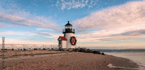 Brand Point Lighthouse, located on Nantucket Island in Massachusetts, decorated for the holidays with a Christmas wreath and crossed oars.  Beautiful clouds surround the lighthouse.