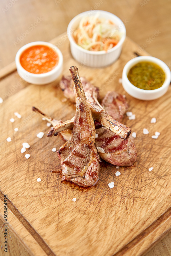 Rack of lamb , grilled meat with bone with Pickled cabbage and two sauces. Serving on a wooden Board. Barbecue restaurant menu, a series of photos of different meats.
