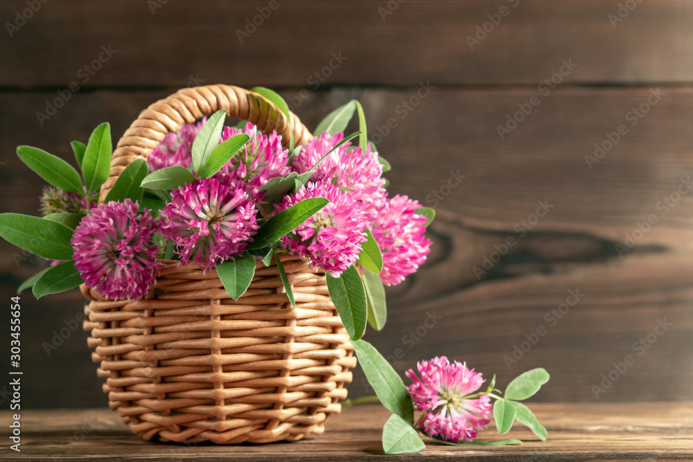 Bouquet of pink clover in a wicker basket on a wooden table on a summer morning