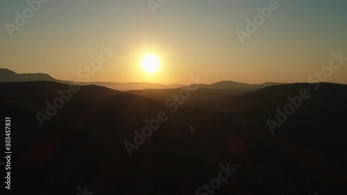 Aerial view of the hills silhouettes against the sun rising over them. Shot. Beautiful morning landscape photo