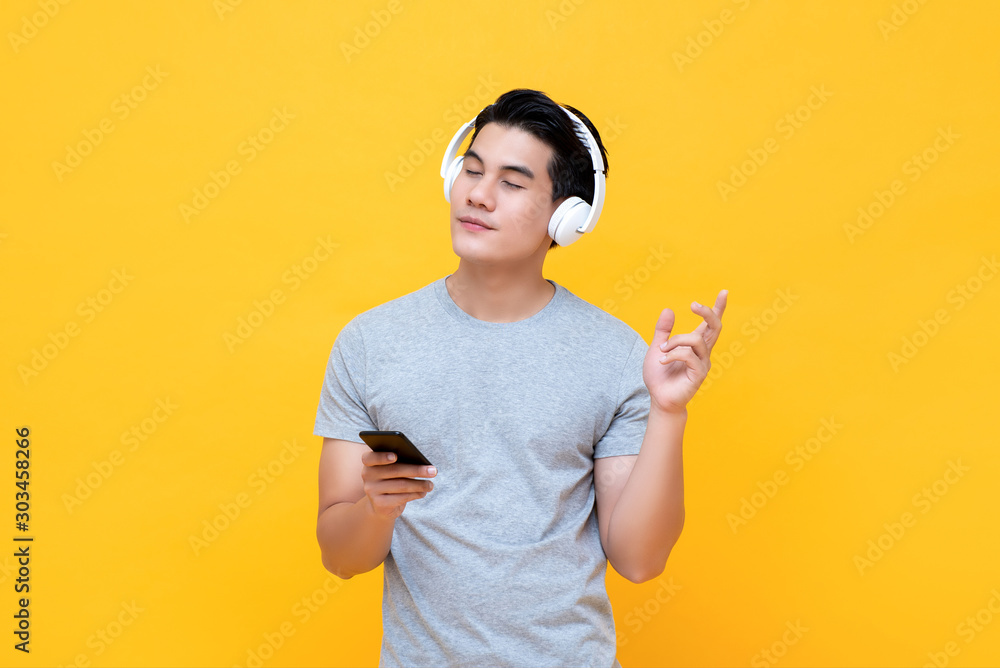 Φωτογραφία Happy man wearing headphones listening to music from smartphone with eye closed