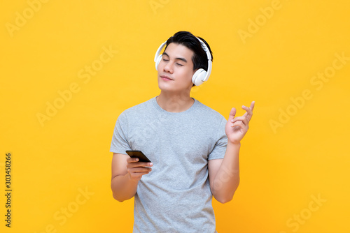 Foto Happy man wearing headphones listening to music from smartphone with eye closed