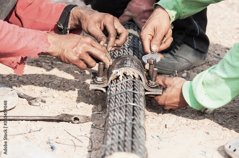 Labor man working with bridge sling tendon bolt tightening construction job - people at site construction working concept
