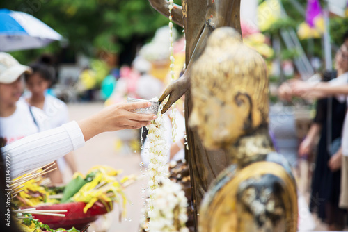 People pouring water onto a Buddha image this is a gesture of worship - people participate the local annual Chiang Mai traditional Bhudist festival. photo