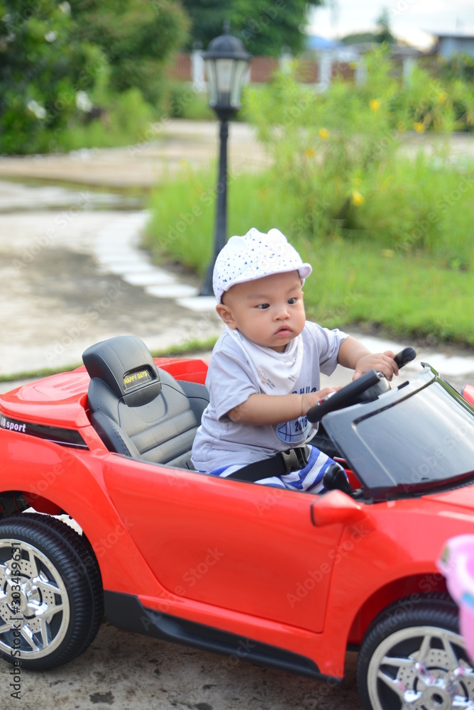 Asian baby boy siting on Toy car