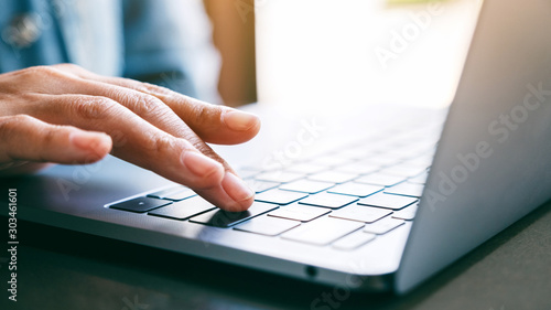 Closeup image of a woman's finger pressing on the enter button of laptop computer on the table photo