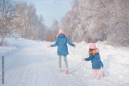 Young woman and little girl run in woods in winter