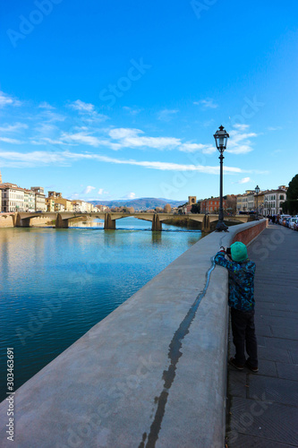 Young tourist boy make a photo of beautiful Arno river in Florence Italy © Sergei Timofeev