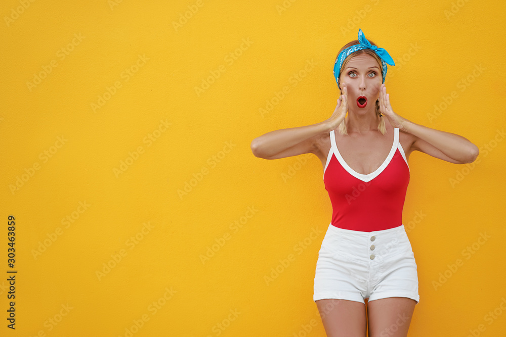 Wow! Shock! Expressing joy! Happy pretty young woman in shorts. Yellow wall background. Wow! Shock! Expressing joy! Happy pretty young woman in shorts. Yellow wall background.