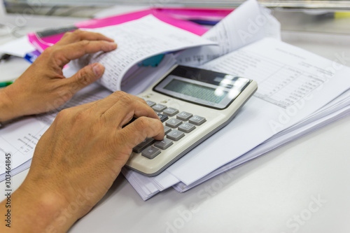 Employees use office calculators with documents of income, expenses, concept of life at work. © piyaphunjun