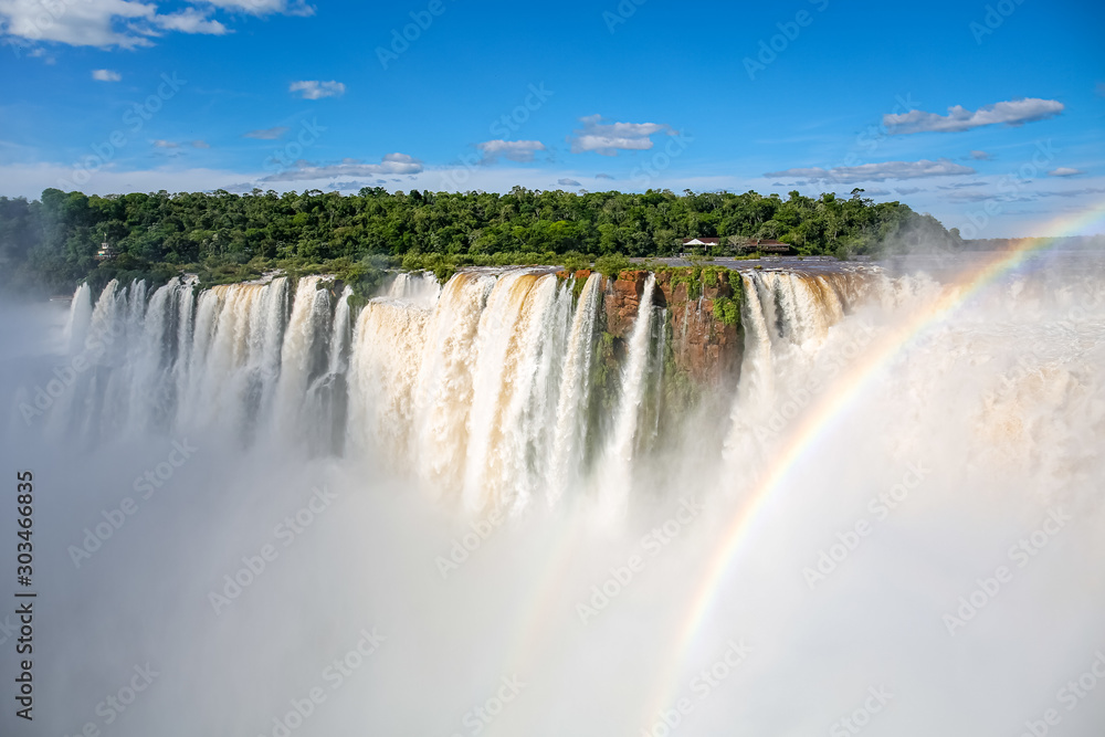 View to Devil`s Throat and Salto Union with rainforest, blue sky, white clouds and small rainbow, Iguazu Falls, Argentina