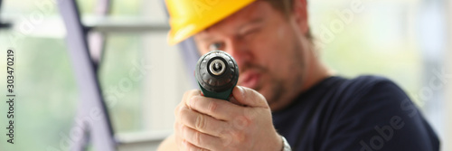 Arms of worker using electric drill closeup