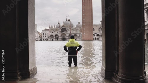 VENICE, ITALY - November 12, 2019: Police man doing surveillance on the St Mark square during the flood  (acqua alta) in Venice, Italy. Venice high water. 4k