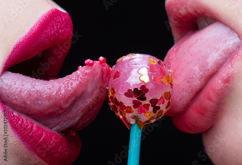 Two woman licking a lollipop covered in heart glitter