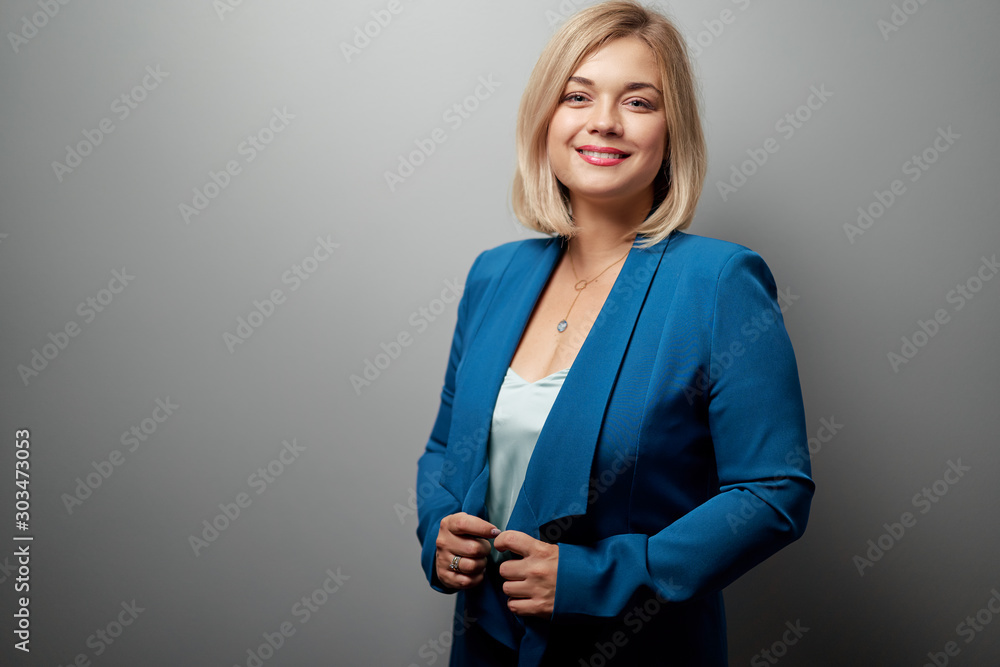 Studio portrait of young business woman looking at camera against grey wall. - obrazy, fototapety, plakaty 