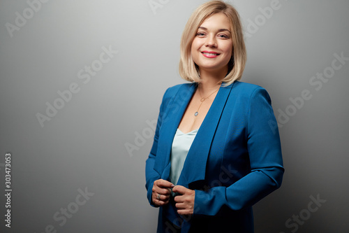 Studio portrait of young business woman looking at camera against grey wall.