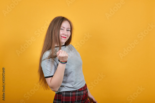 Young caucasian lady wearing gray shirt looking so funny, over white wall happy and pointing to the side, keeping fist up