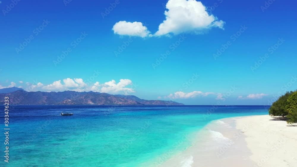 Beautiful white clouds on bright blue sky hanging over mountains surrounding azure sea with calm water, washing exotic beach in Antigua Beautiful white clouds on bright blue sky hanging over mountains surrounding azure sea with calm water, washing exotic beach in Antigua