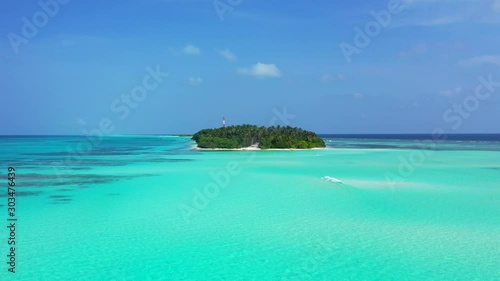 Fiji, South Pacific - The Lush Green Island Surrounded By The Shallow Ocean Under The Bright Blue Sky - Wide Shot   photo