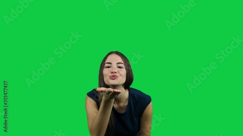 Sexy attractive girl blowing a kiss in front of a green screen photo