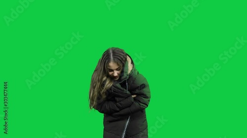 Girl freezing with warm jacket in front of a green screen photo