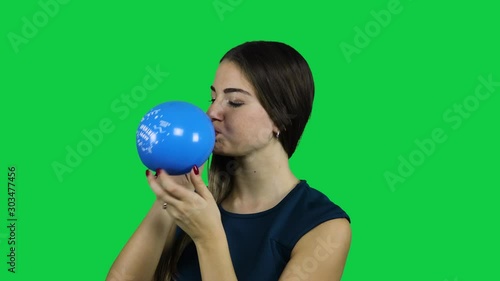 Girl blowing up a balloon in front of a green screen photo
