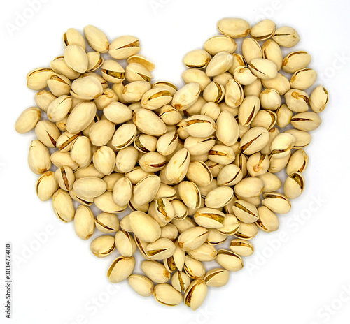 heart shaped pistachios on top in wooden bowl  isolated on white background