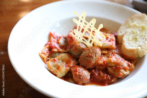 Homemade spinach Ravioli pasta with sausage in tomato sauce on wood background , italian traditional food