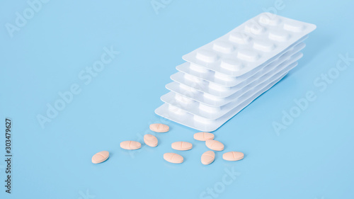 Orange statins tablets pill and white blister pack for light resistance packaging isolated on blue background, medicine for decrease blood cholesterol level and maintain cardiovascular system