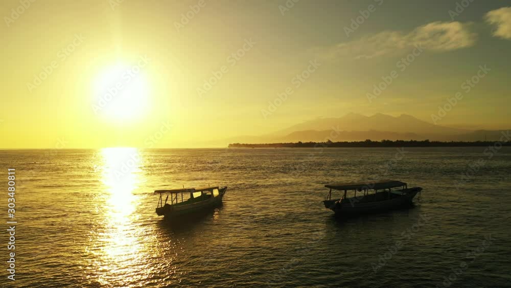 Golden magical sunset reflecting on calm sea surface where long boats anchored after finishing the journey around exotic coastline of Malaysia Golden magical sunset reflecting on calm sea surface where long boats anchored after finishing the journey around exotic coastline of Malaysia