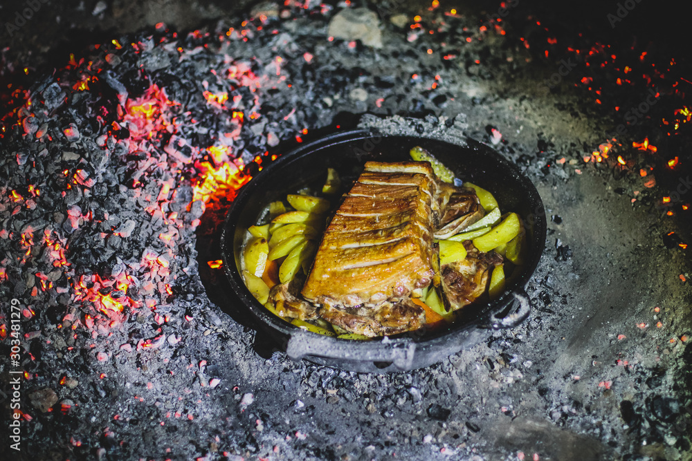 Foto de Cooking of peka, podpeka on open fire grill at night. Traditional food in croatia or