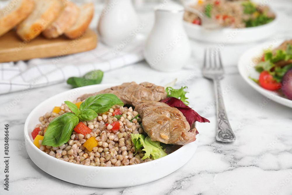 Tasty buckwheat porridge with meat on white marble table Tasty buckwheat porridge with meat on white marble table