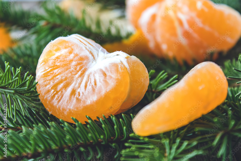 Ripe peeled slices of tangerine without peel lie on the green branches of a Christmas tree. Ripe peeled slices of tangerine without peel lie on the green branches of a Christmas tree.