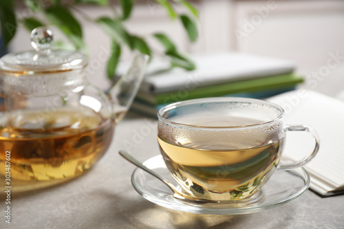 Tasty hot green tea in cup on grey table