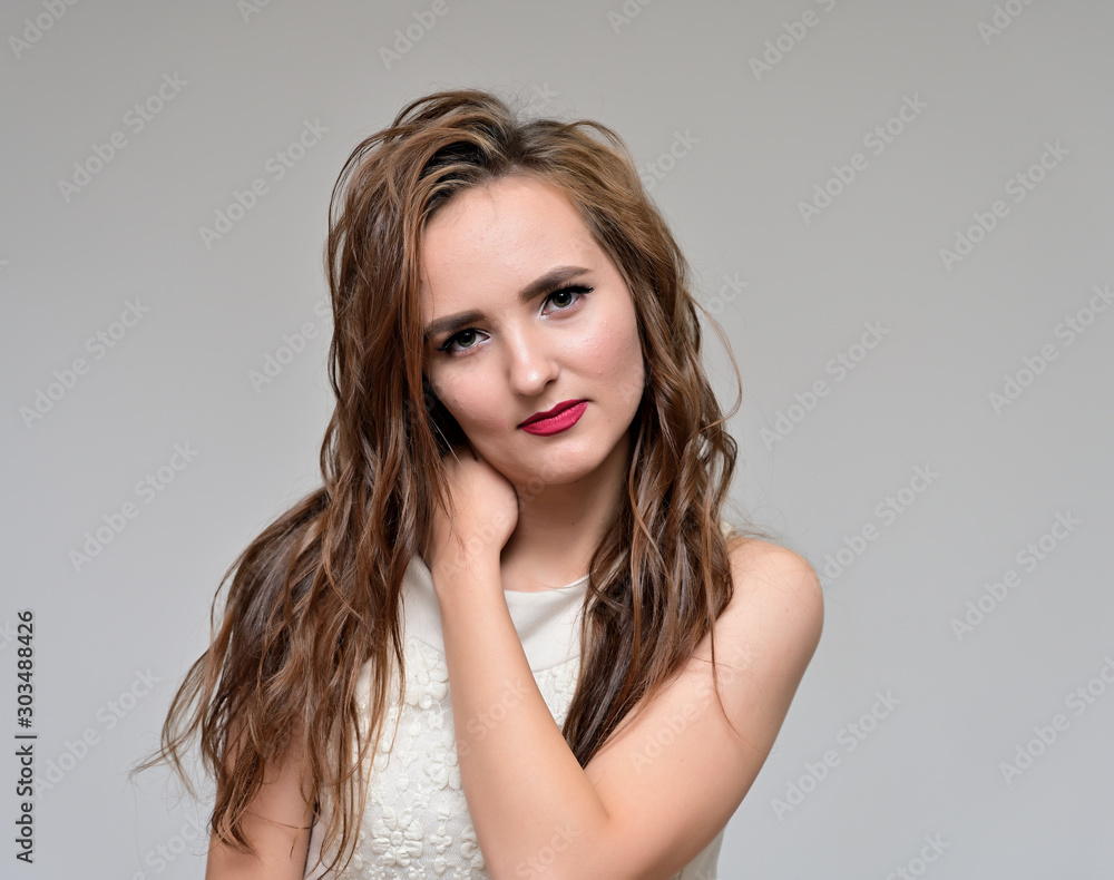 The concept of beauty, fashion, makeup, cosmetics. Portrait of a nice young pretty brunette girl with beautiful hairstyle, great makeup, long curly hair on a gray background. The concept of beauty, fashion, makeup, cosmetics. Portrait of a nice young pretty brunette girl with beautiful hairstyle, great makeup, long curly hair on a gray background.