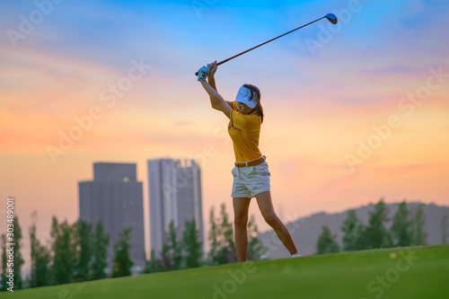 woman golf player in action being top of backswing ready to hit the golf ball away from T-OFF to destination in fairway,