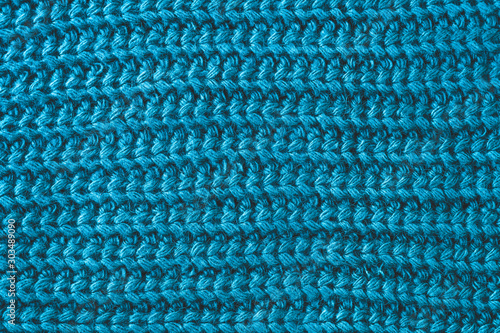Texture of woolen knitted scarf. Yarn with knitting. Ornament of a blue knitted sweater. Abstract textile background.