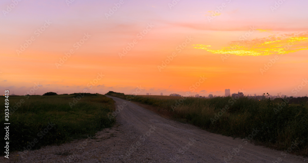 Empty dirt road to golden sunset