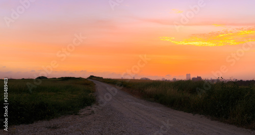 Empty dirt road to golden sunset