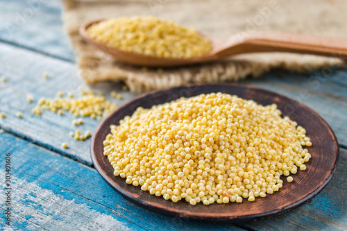 Dry yellow millet in a bowl on a background of old blue boards.