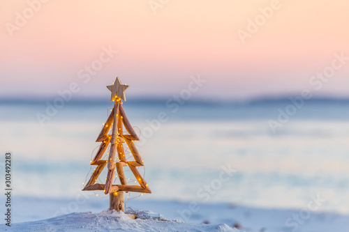 Christmas tree with fairy lights on the beach in summer