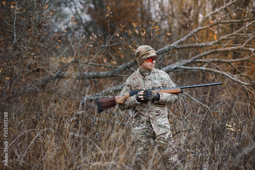 Hunter handsome guy with weapon. Hunter spend leisure hunting. Hunting equipment. Brutal masculine hobby. Man observing nature background. Hunter hold rifle. Safety measures. Natural environment.