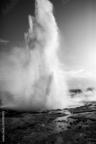 Eruption of Strokkur geyser in Iceland. Winter cold colors, sun lighting through the steam. Geothermal area in Iceland