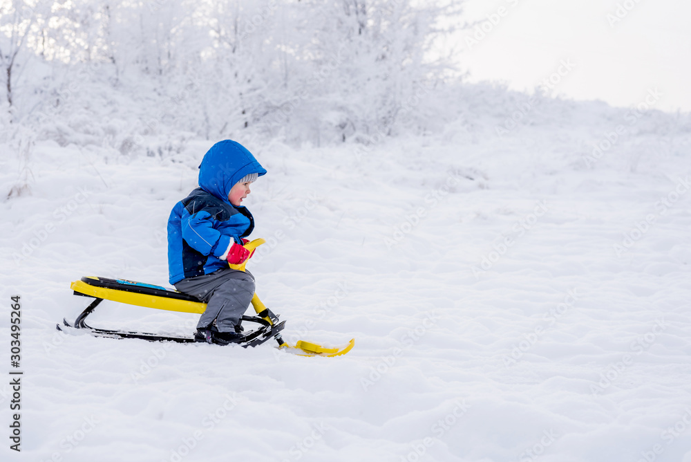 little child riding a snow scooter in winter