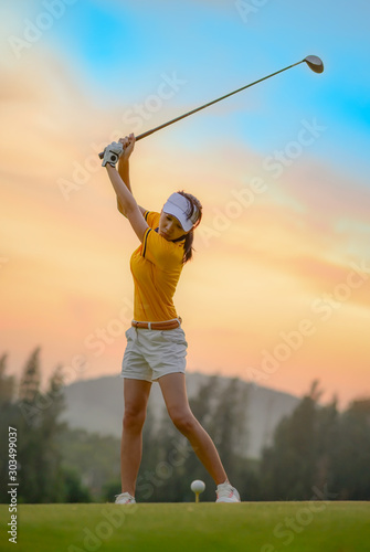woman golf player in action being top of backswing ready to hit the golf ball away from T-OFF to destination in fairway,