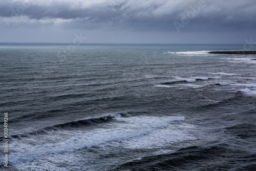 Beautiful coast of the Atlantic ocean with mountains. Waves of the North Atlantic ocean crashing against the beach in iceland after a storm.