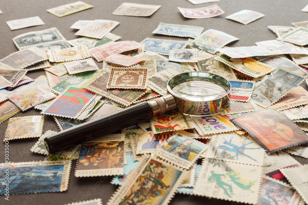 Lutsk, Ukraine - May 5th, 2018: Still life with stamps and magnifying glass. Various old postage stamps